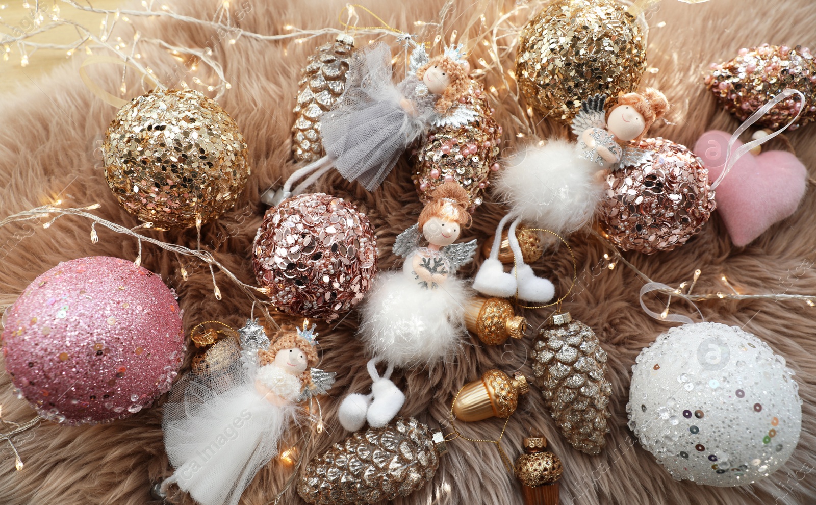 Photo of Beautiful Christmas tree baubles, toys and fairy lights on faux fur, above view