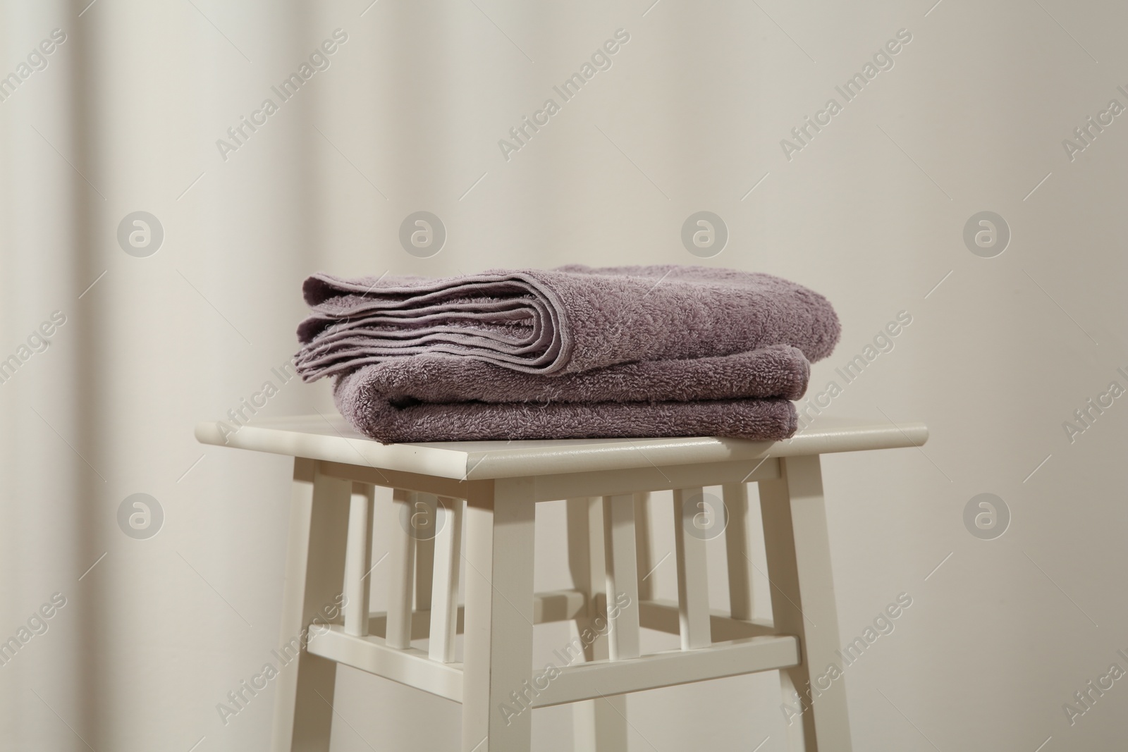 Photo of Violet towels on stool against white wall