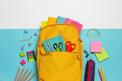 Backpack with different school stationery on color background, flat lay
