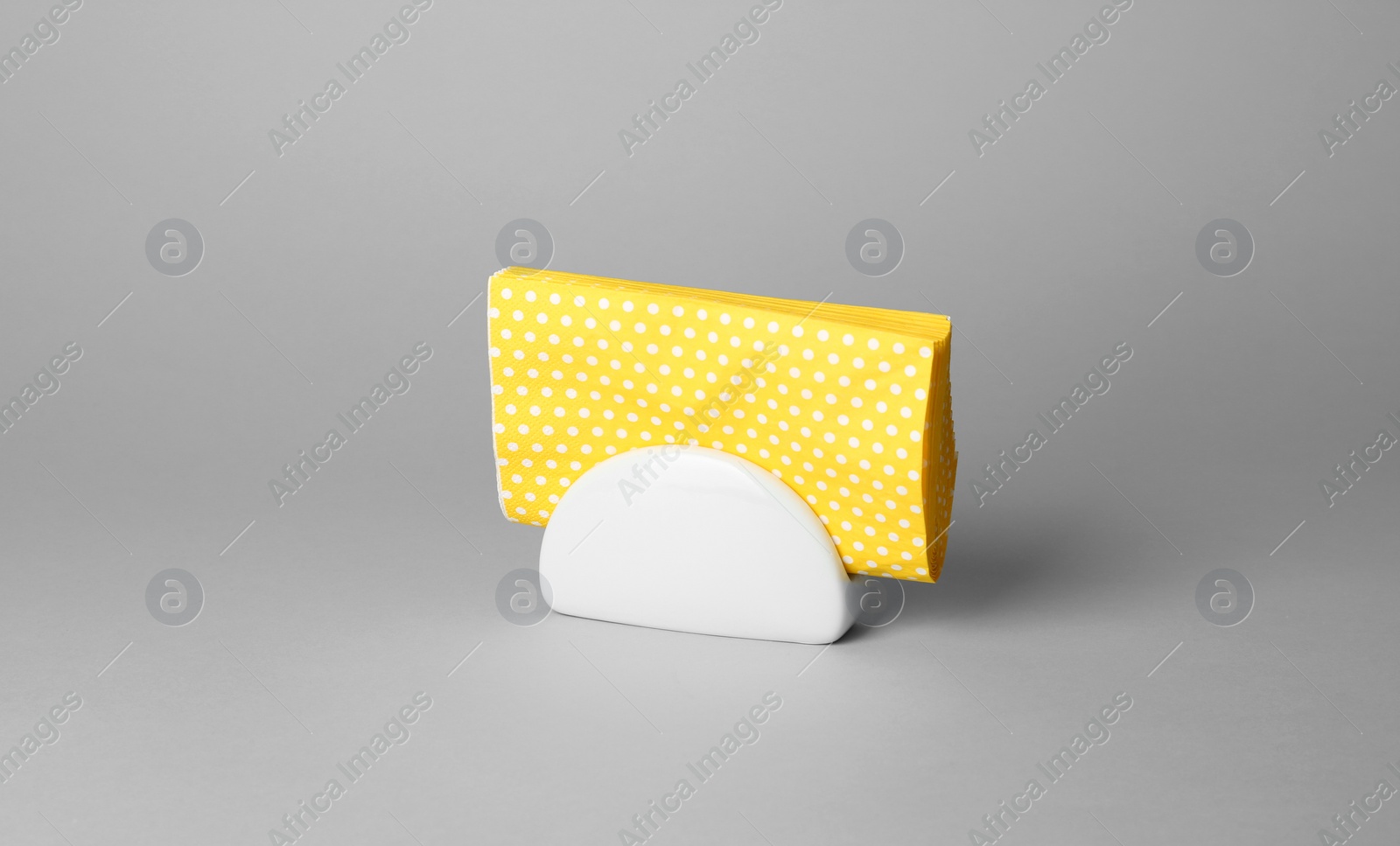 Photo of Ceramic napkin holder with paper serviettes on gray background