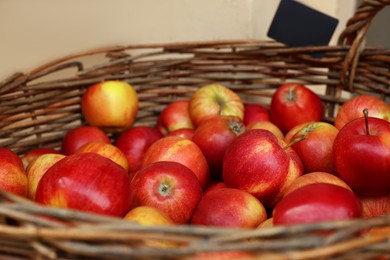Fresh ripe apples in wicker basket at market, closeup