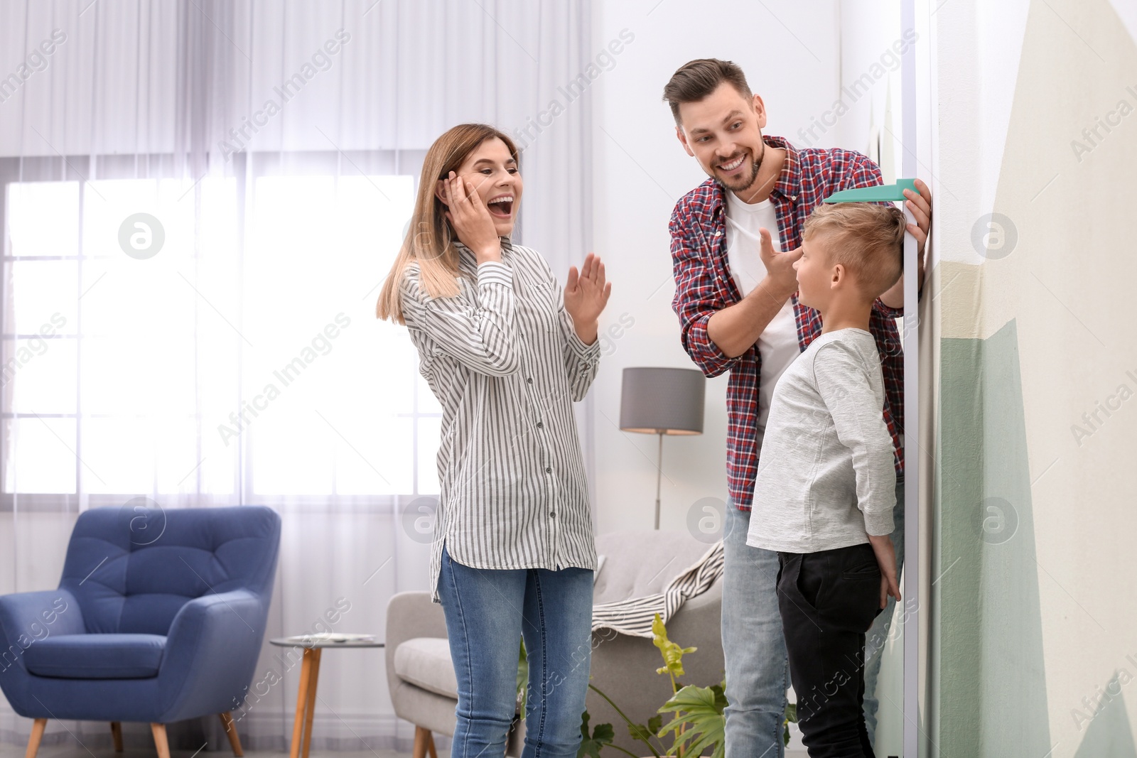 Photo of Parents measuring their son's height at home