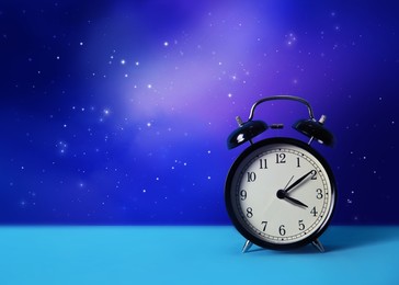 Image of Alarm clock on turquoise table against night sky with stars, space for text. Insomnia