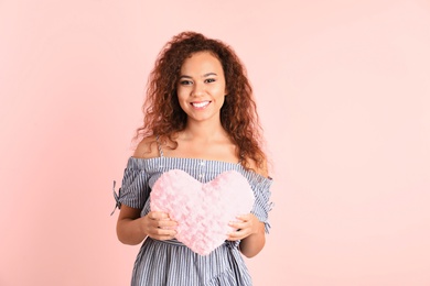 Photo of African-American woman with fluffy heart on color background