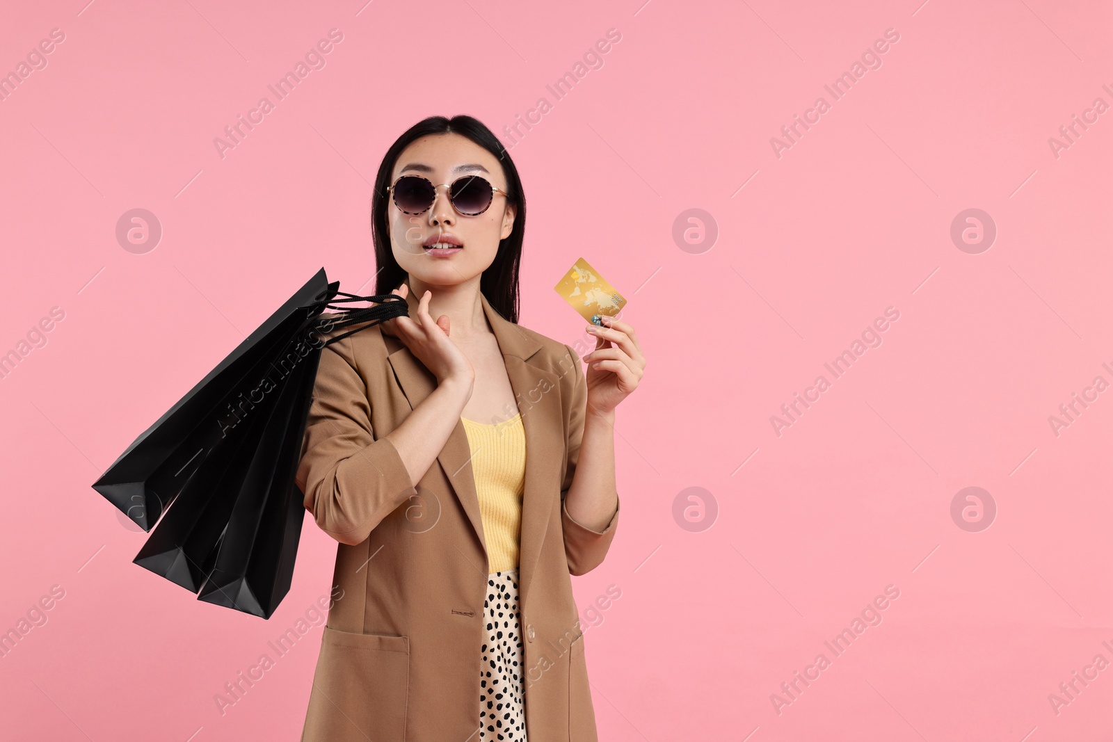 Photo of Beautiful woman with shopping bags and credit card on pink background. Space for text