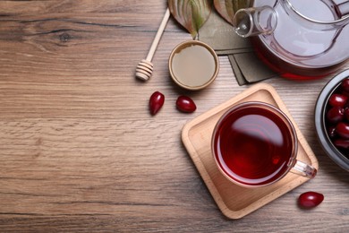 Flat lay composition with fresh dogwood tea and berries on wooden table. Space for text