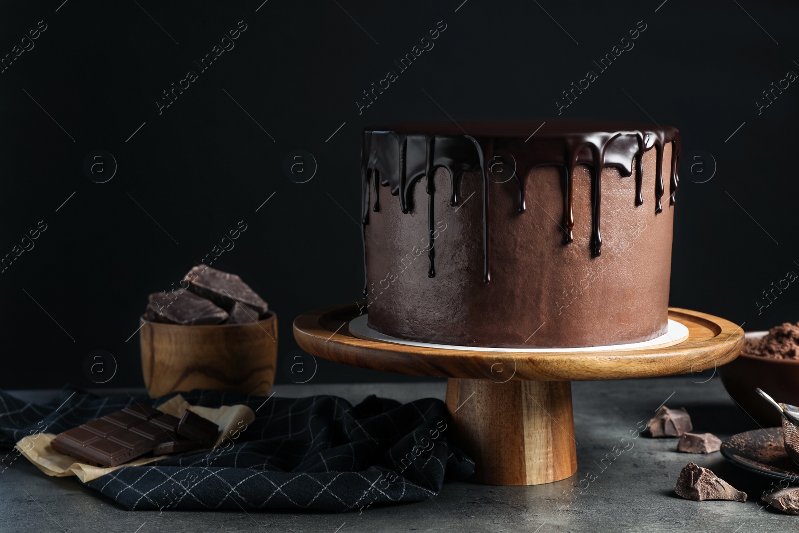 Photo of Freshly made delicious chocolate cake on grey table against black background