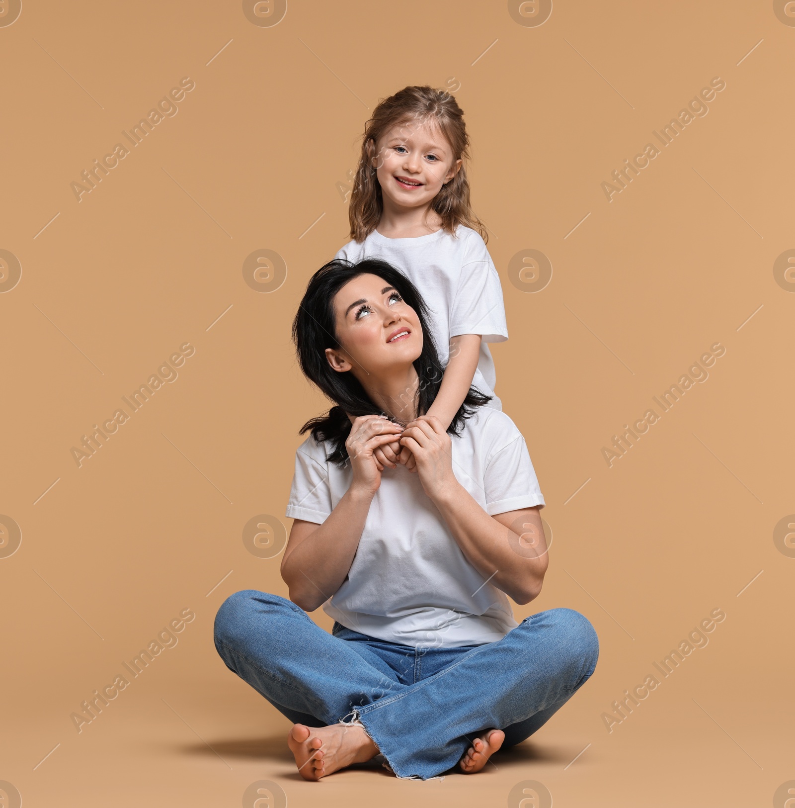 Photo of Beautiful mother with little daughter on beige background