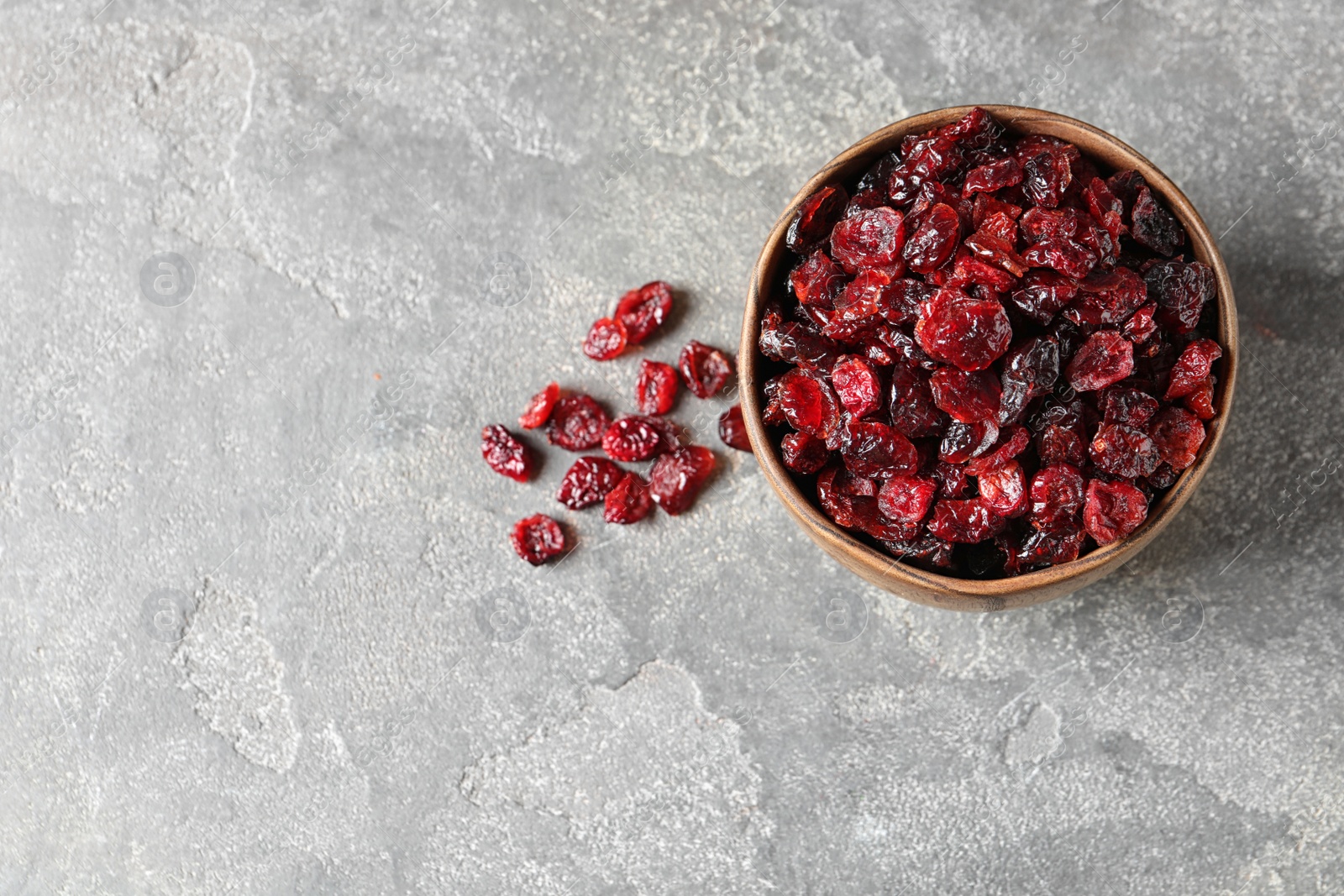 Photo of Bowl of sweet cranberries on color background, top view with space for text. Dried fruit as healthy snack