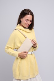 Fashionable young woman with stylish bag on light background