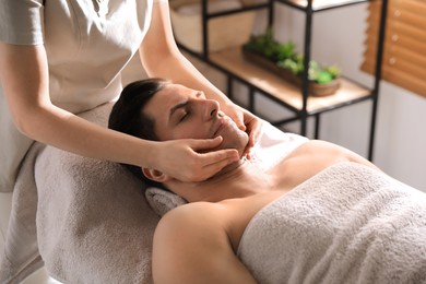 Photo of Man receiving facial massage in beauty salon