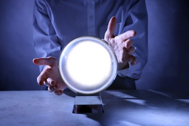 Photo of Businesswoman using crystal ball to predict future at table, closeup