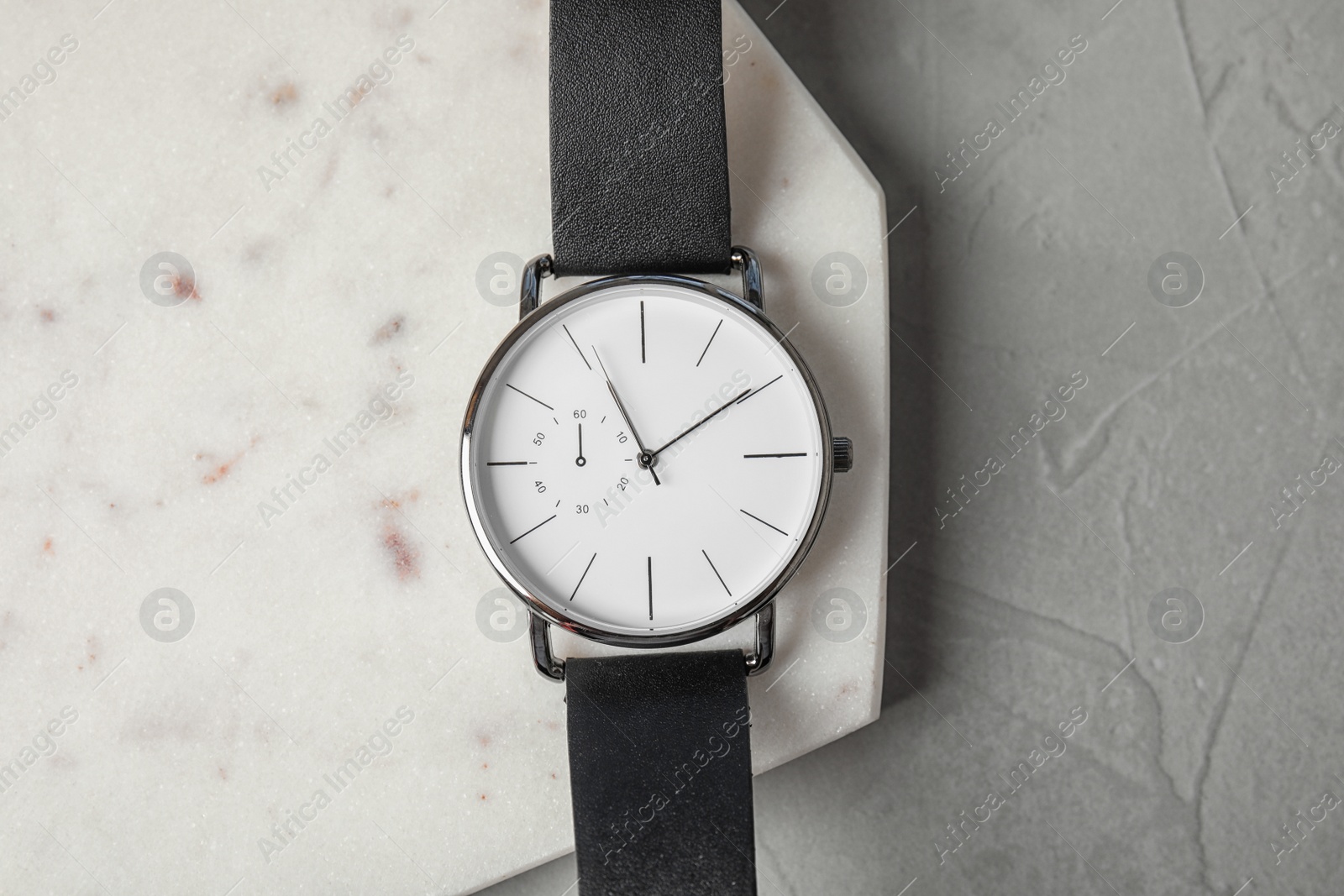 Photo of Board with stylish wrist watch on gray table, top view. Fashion accessory