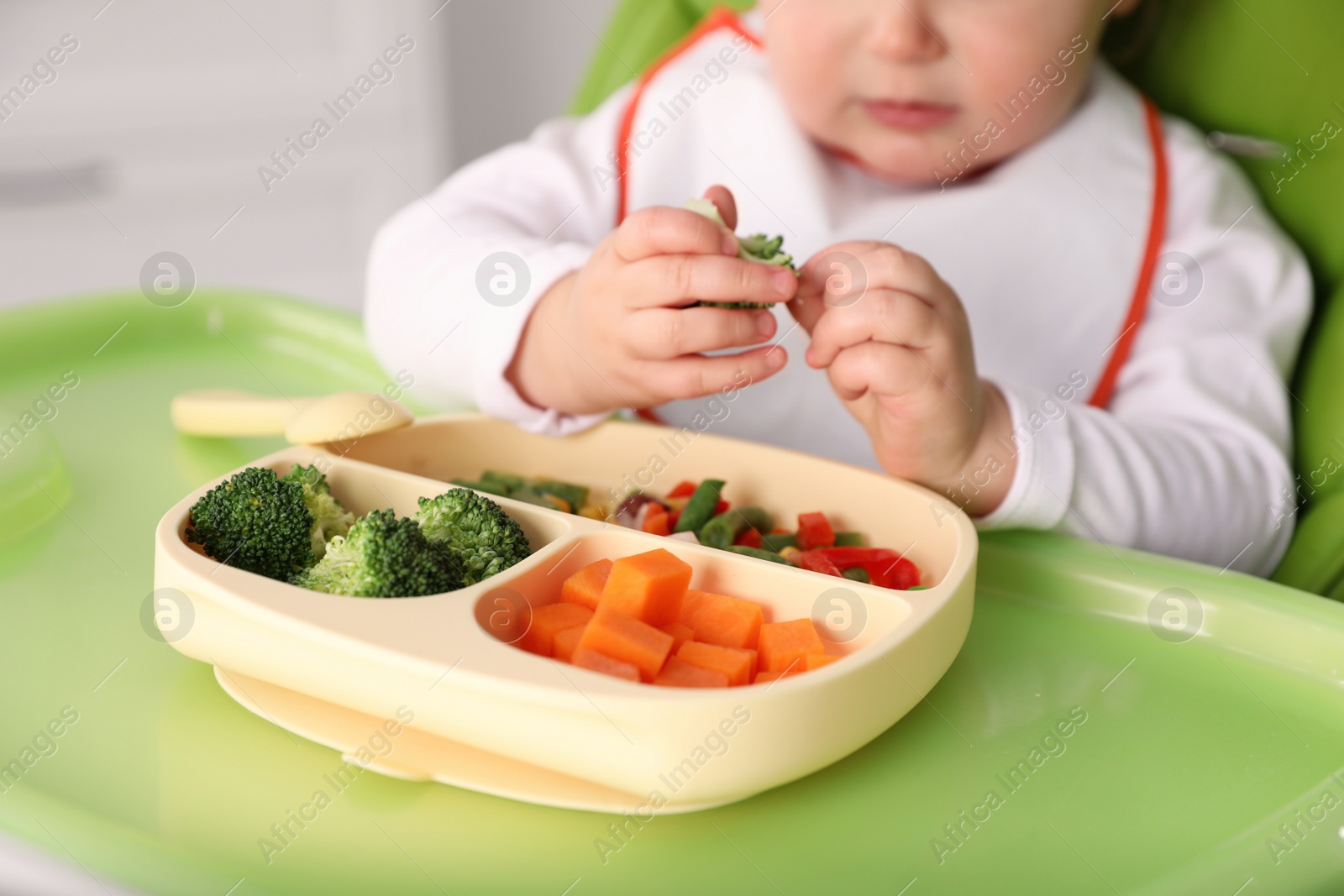 Photo of Little baby eating food in high chair, closeup