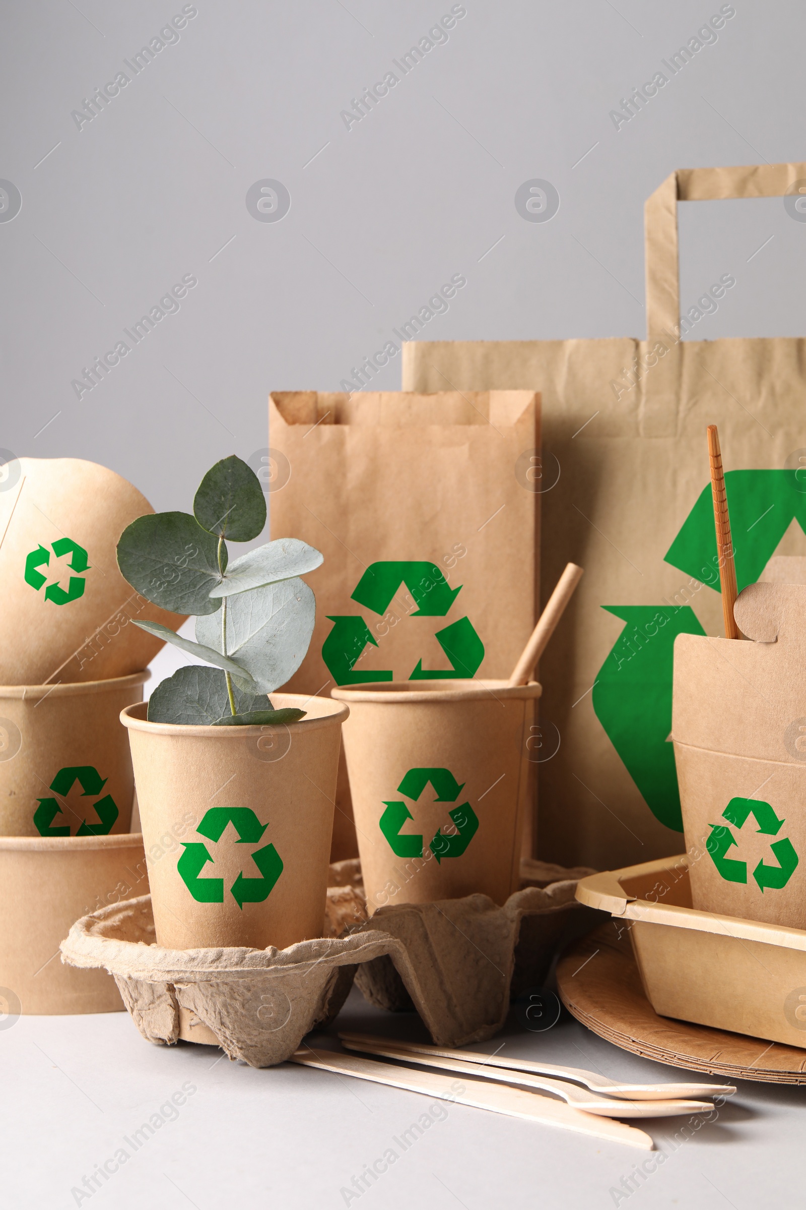 Image of Set of eco friendly food packaging with recycling symbols on light background