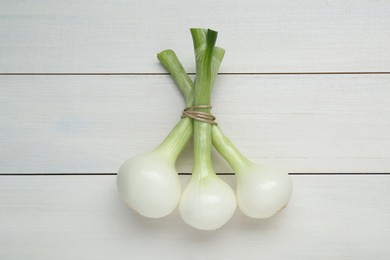 Bunch of green spring onions on white wooden table, flat lay