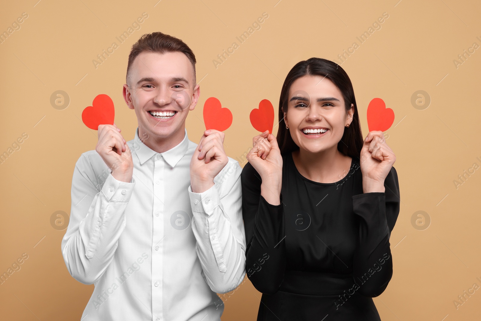 Photo of Lovely couple with decorative hearts on beige background. Valentine's day celebration