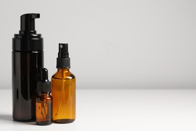 Photo of Bottles with oil on white table, space for text. Natural cosmetics