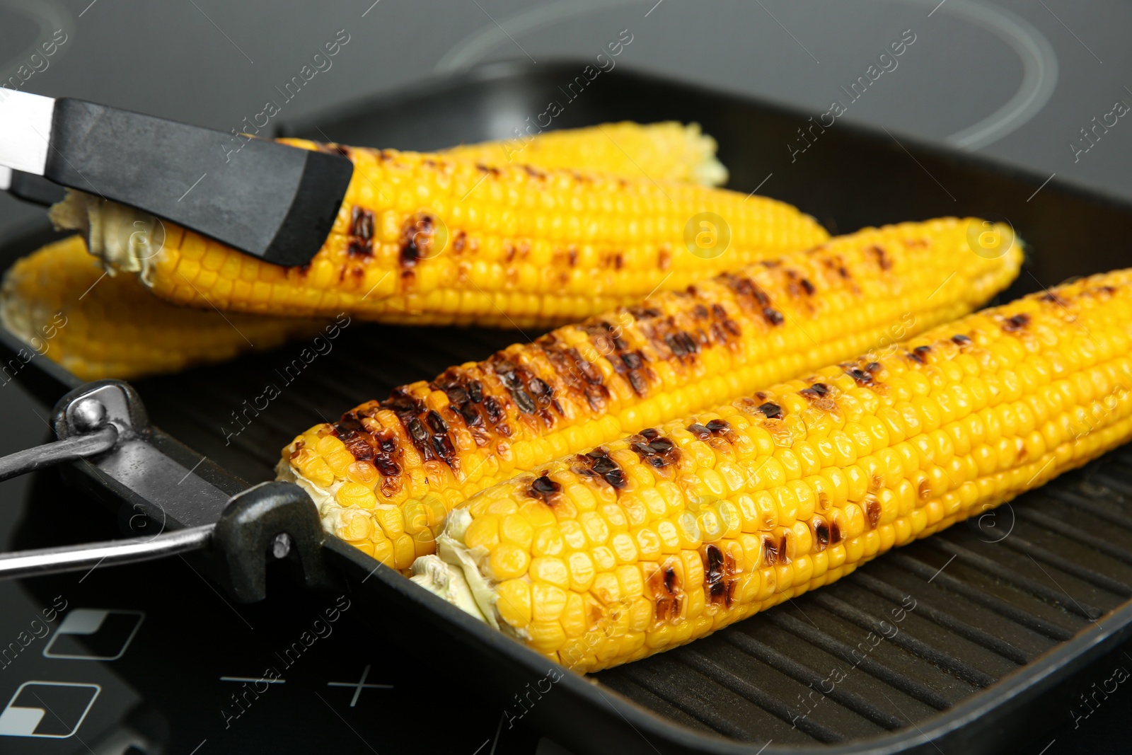 Photo of Cooking fresh corn cobs on grill pan, closeup