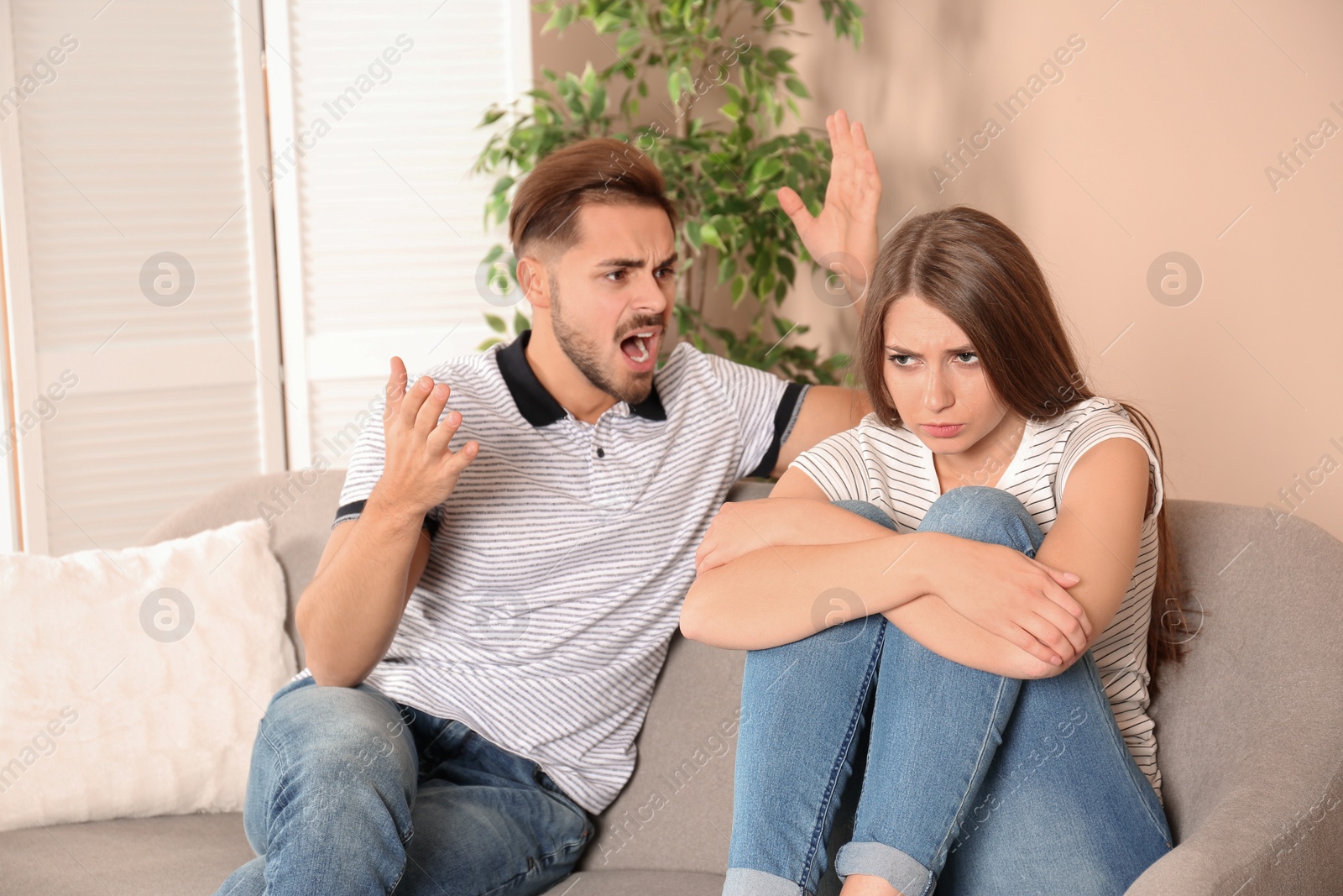 Photo of Young couple arguing in living room. Relationship problems