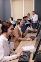 Call center operators working in modern office, focus on young woman with headset