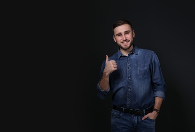 Photo of Man showing THUMB UP gesture in sign language on black background, space for text