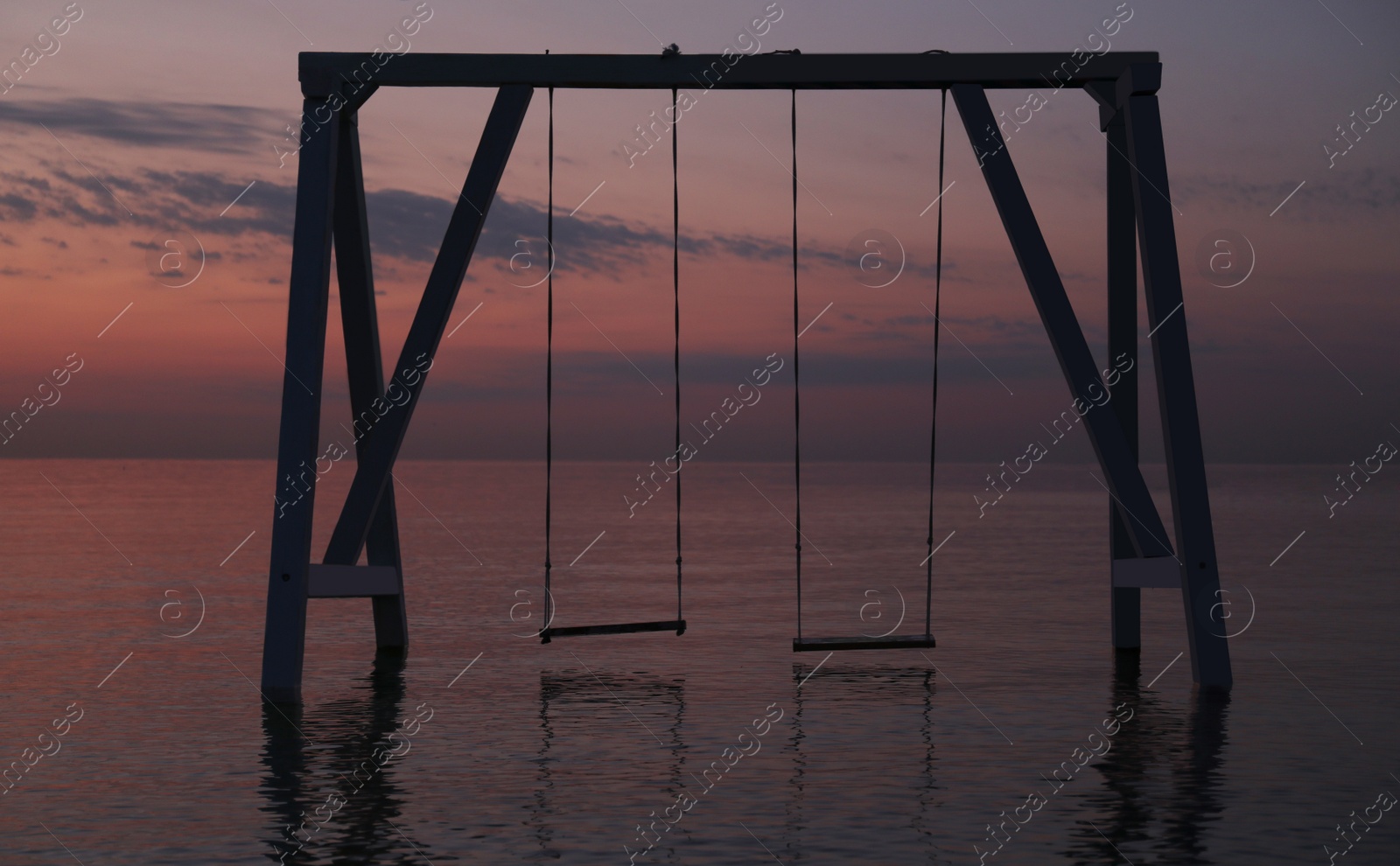 Photo of Picturesque view of swing in water on sunrise