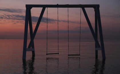 Picturesque view of swing in water on sunrise