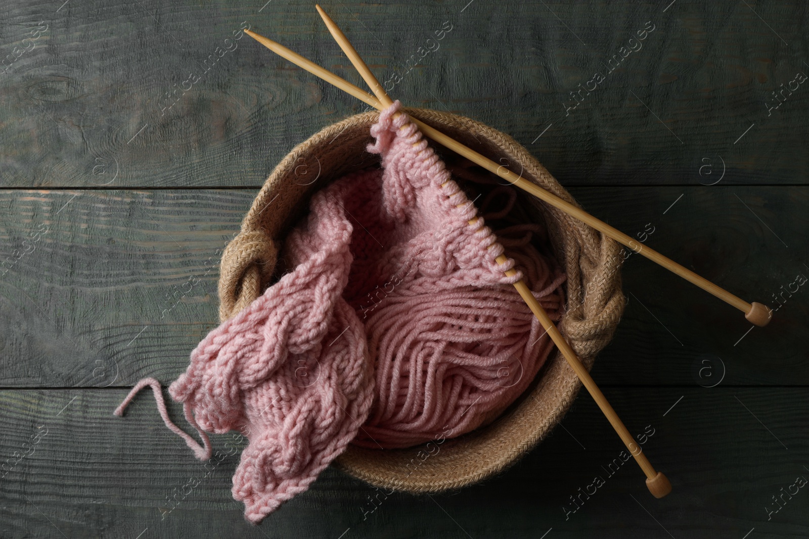 Photo of Soft pink woolen yarn, knitting and needles on wooden table, top view