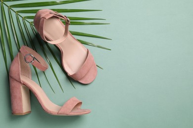 Photo of Pair of stylish high heeled shoes and palm branch on green background, flat lay. Space for text