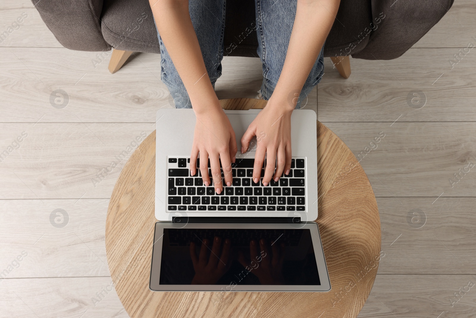 Photo of Woman working with laptop at wooden table, top view. Space for text