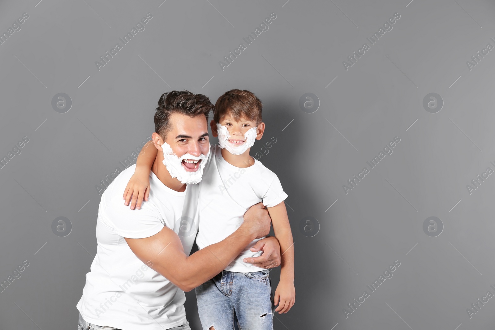 Photo of Father and son with shaving foam on faces against color background. Space for text