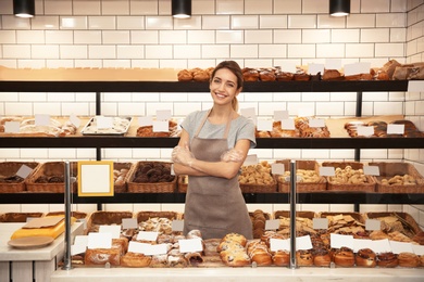 Beautiful woman near showcase with pastries in bakery shop