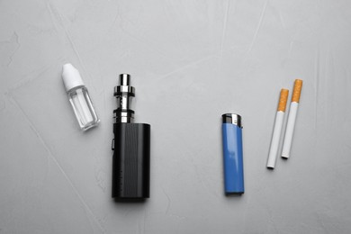 Photo of Cigarettes with lighter and vaping device on grey background, flat lay. Smoking alternative