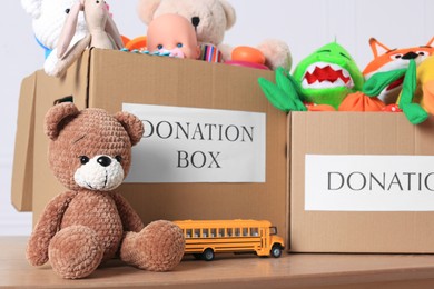Donation boxes and different child toys on wooden table