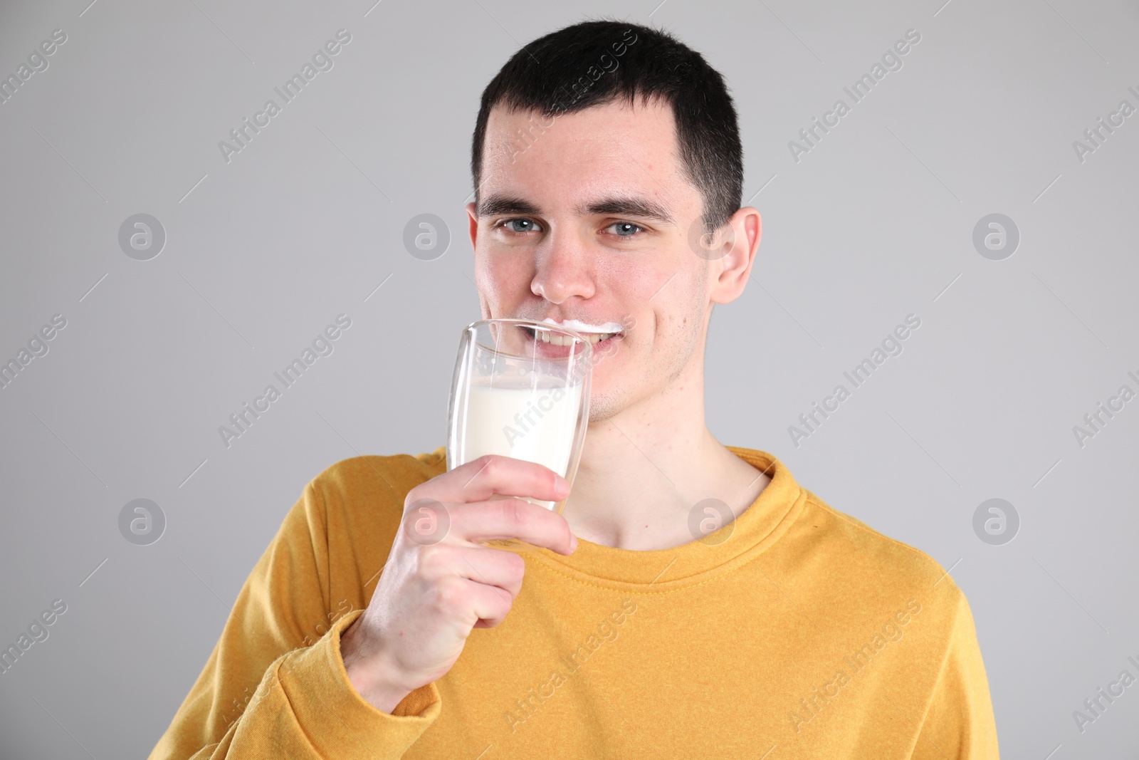 Photo of Milk mustache left after dairy product. Man drinking milk on gray background