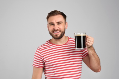 Handsome man with cold kvass on light grey background. Traditional Russian summer drink