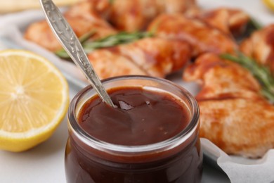 Photo of Fresh marinade with spoon in jar on table, closeup