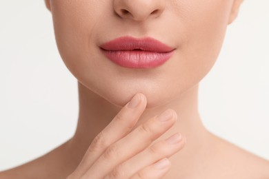 Young woman with beautiful full lips on white background, closeup