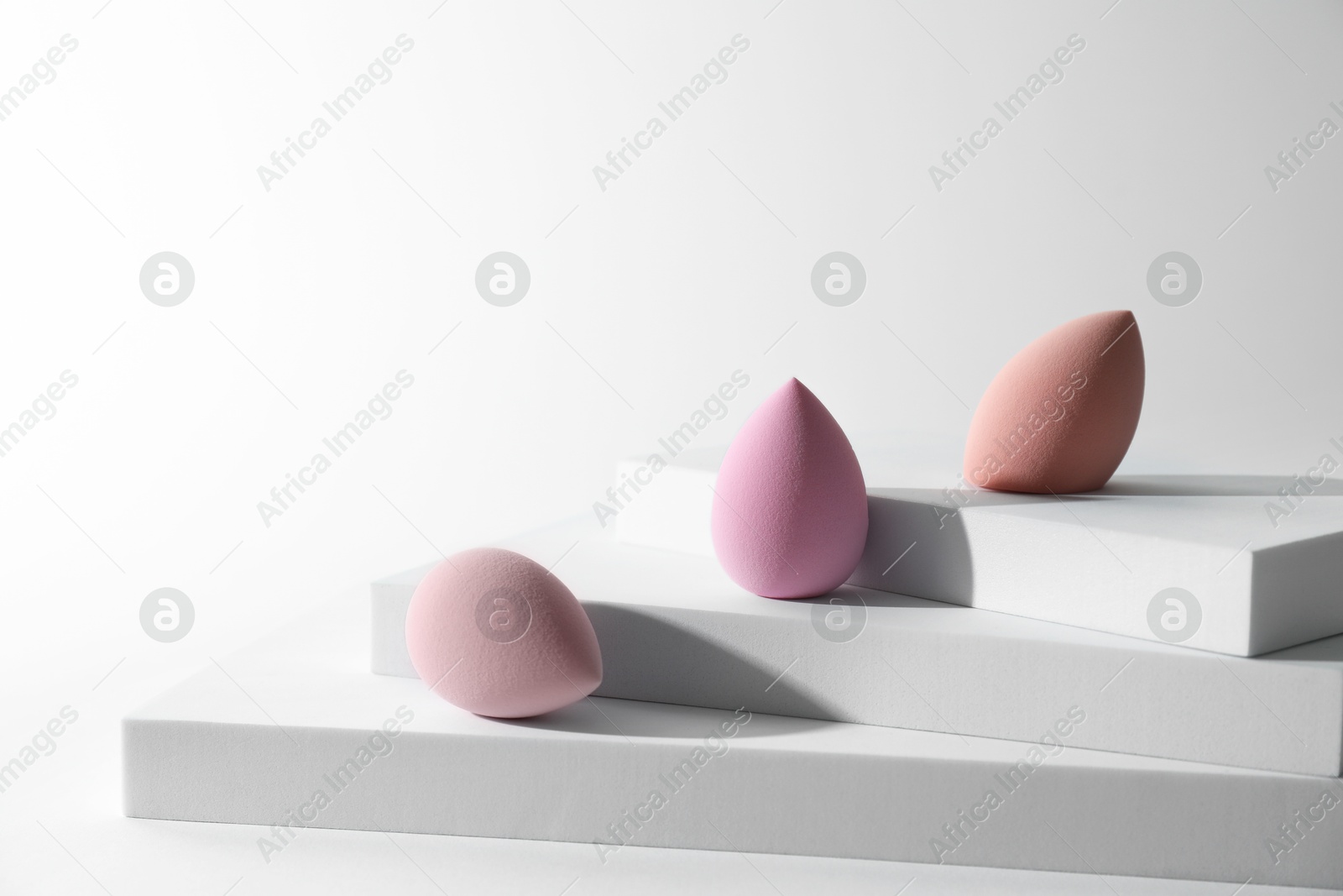 Photo of Stylish presentation of makeup sponges on white background, space for text