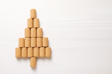 Photo of Christmas tree made of wine corks on white wooden table, top view. Space for text
