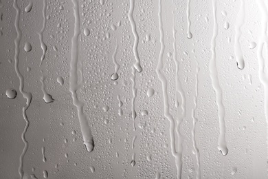 Photo of Glass with rain drops against light background