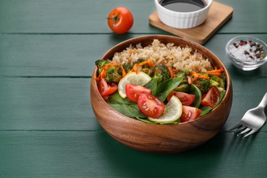 Tasty fried rice with vegetables served on green wooden table, closeup. Space for text