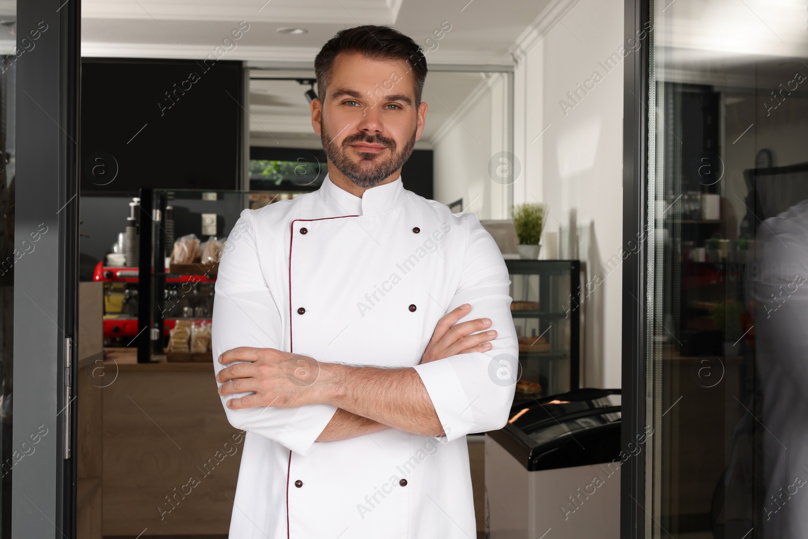 Photo of Happy baker in uniform at door of his cafe