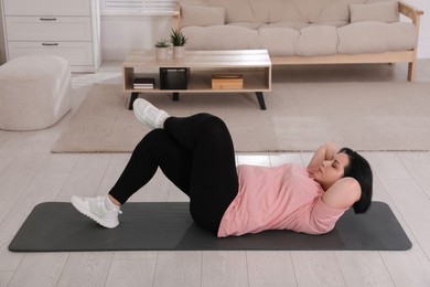 Overweight mature woman doing abs exercise at home