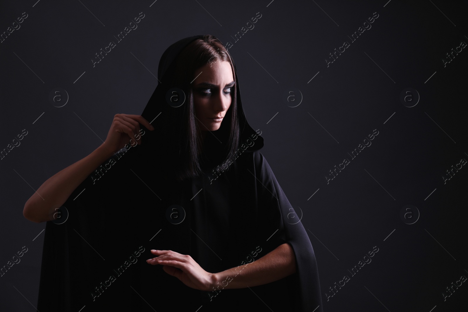 Photo of Mysterious witch with spooky eyes on black background