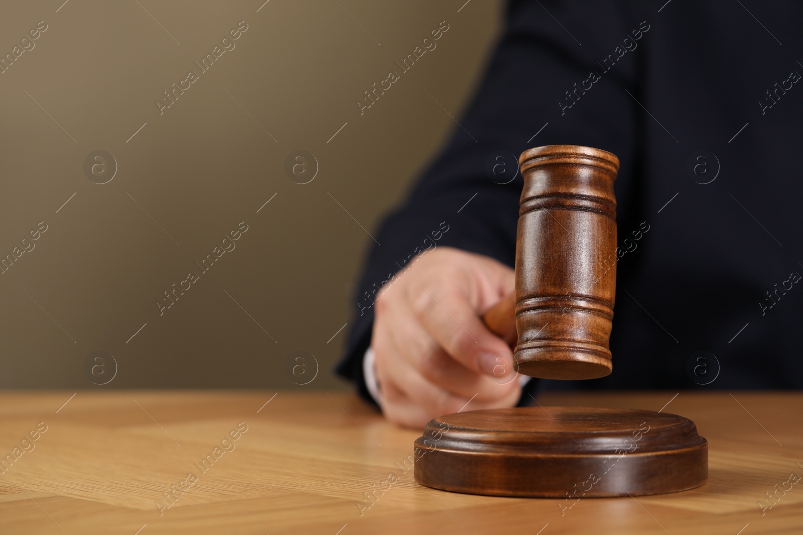 Photo of Man with gavel at wooden table, closeup. Space for text