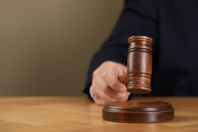 Photo of Man with gavel at wooden table, closeup. Space for text