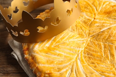 Traditional galette des Rois with paper crown on table, closeup