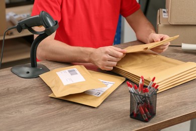 Photo of Post office worker with adhesive paper bags at counter indoors, closeup